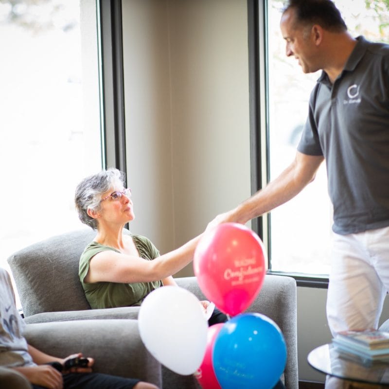 Dr. Comella congratulating a young patient with balloons at Comella Orthodontics in Rochester, NY