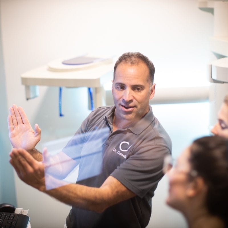 Dr. Comella showing a patient orthodontic retainers at our Rochester, NY office