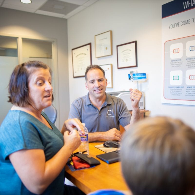 Dr. Comella and a team member sharing tips for life with braces with a Rochester family